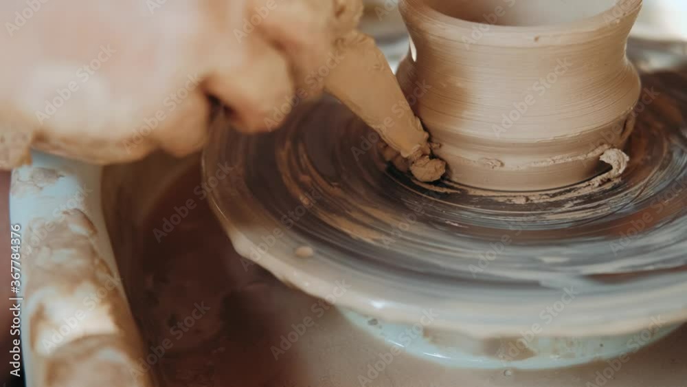 Creating vase of white clay close-up. The sculptor in workshop makes jug out of clay closeup. Twisted potter's wheel. Master crock. Potter's work close-up. Man hands making clay jug. Handmade. Craft. Creating vase of white clay close-up. The sculptor in workshop makes jug out of clay closeup. Twisted potter's wheel. Master crock. Potter's work close-up. Man hands making clay jug. Handmade. Craft.