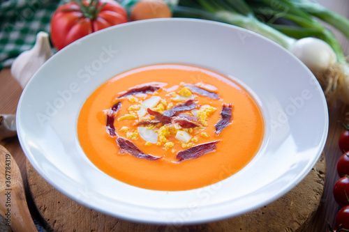Traditional spanish Salmorejo. Cold tomato soup made with garlic, tomatoes, onion, bread and served with olive oil, iberico ham and boiled egg. photo