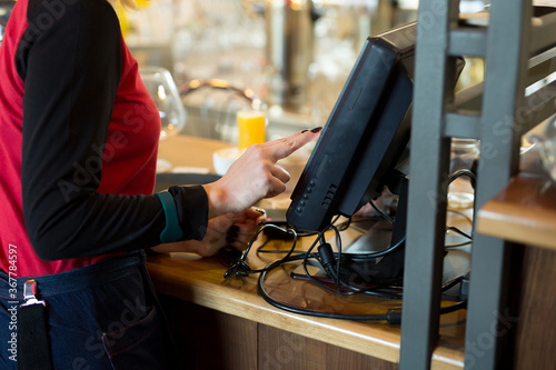 A waiter of a modern cafe or bar enters an order or payment via a tablet or a seekipper