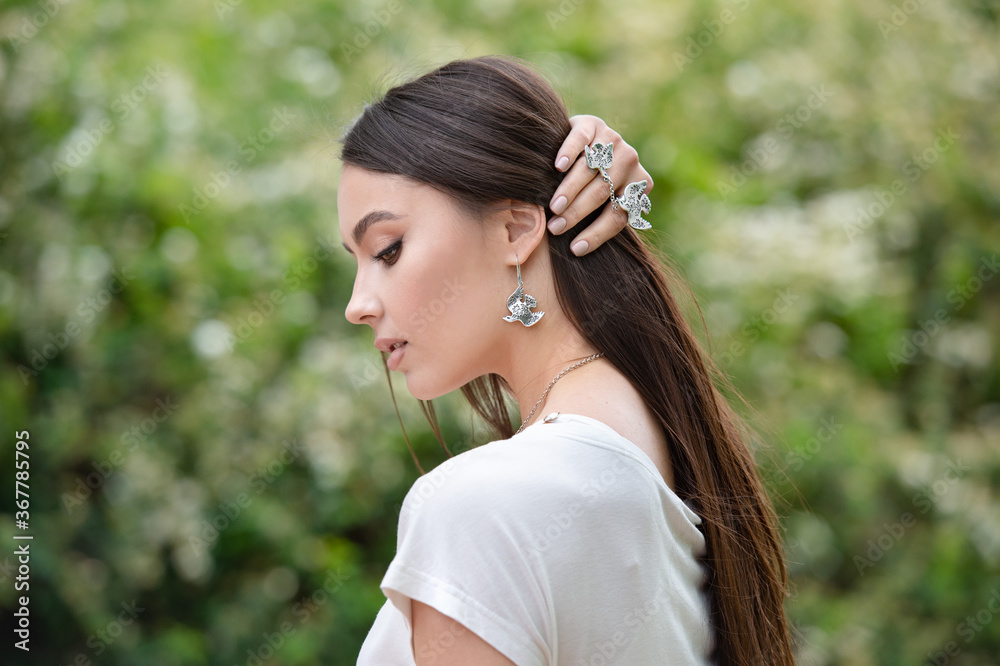 Close-up of the neck of a beautiful young blonde in a shirt with silver earrings