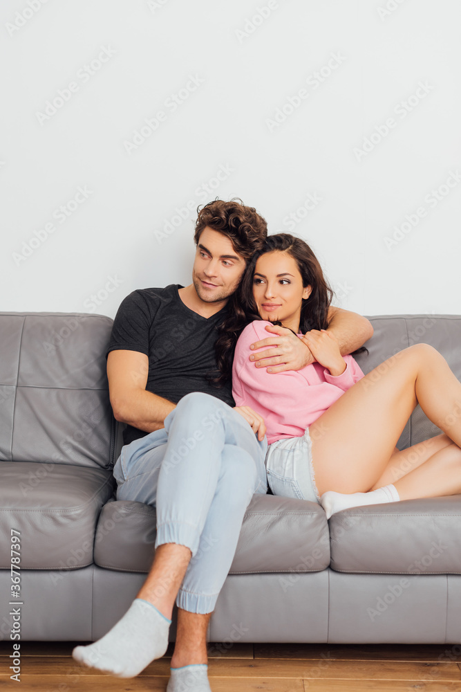 Selective focus of handsome man embracing beautiful girlfriend on sofa at home Selective focus of handsome man embracing beautiful girlfriend on sofa at home