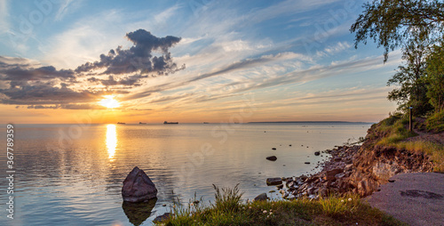 Silhouette of ships on background out at sea at cloudy sunset