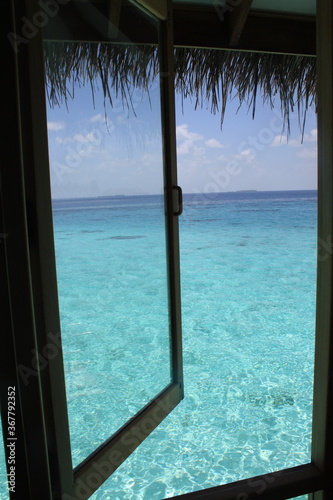 Iconic and beautiful view from an overwater bungalow on the turquoise blue water of the Indian ocean in Maldives island.