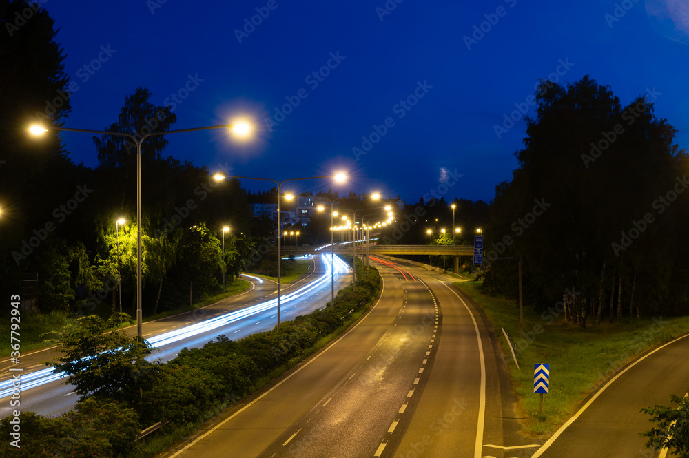 Light trails of passing by cars on nearly empty highway on cloudless night.