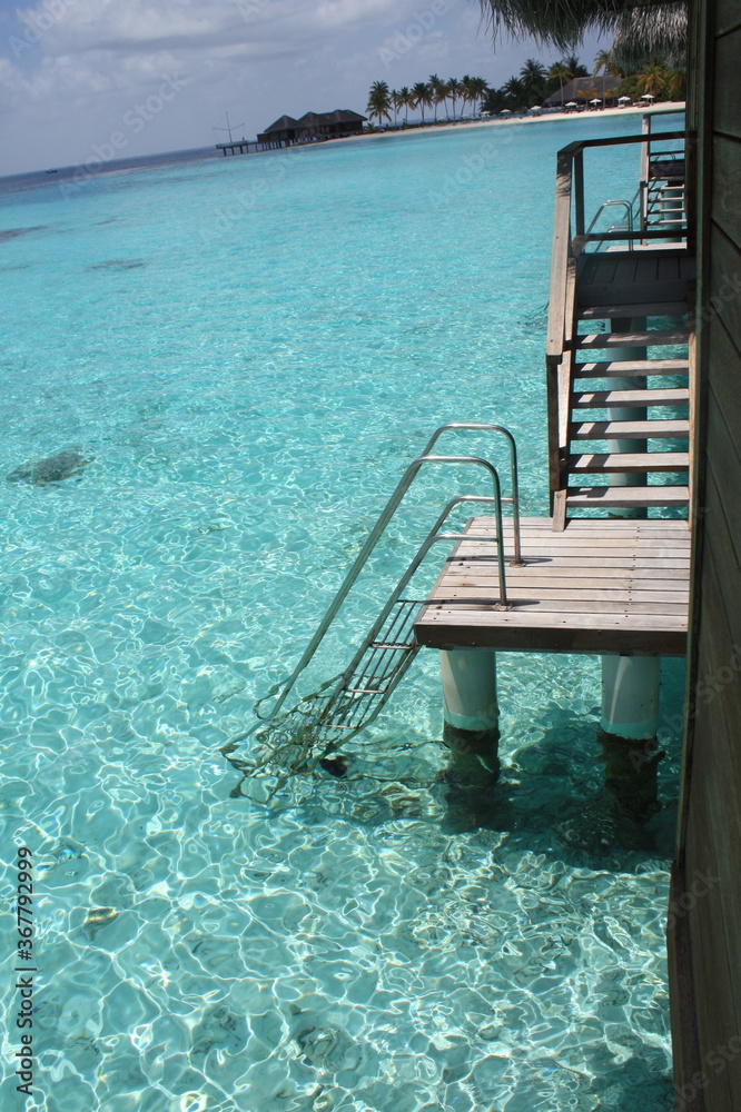 Beautiful isolated ladder of an overwater bungalow, down directly to the beautiful turquoise blue sea of a laggon in Indian ocean, Maldives.