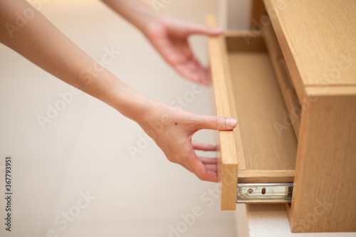 Woman hand pull open drawer wooden cabinet. © marchsirawit