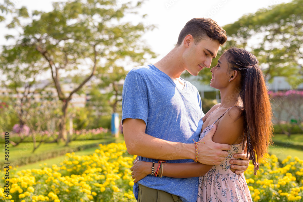 Fototapeta premium Portrait of young multi ethnic couple relaxing together at the park