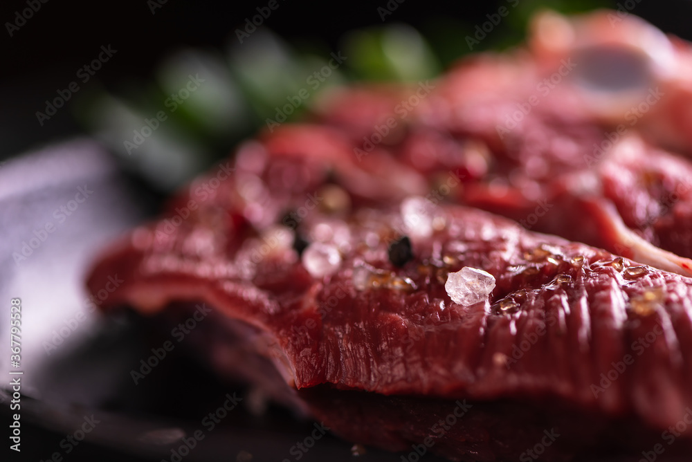 Fresh Raw Meat for Steak New York, Decorated with Herbs and Sprinkled with Mixed Pepper and Coarse Salt, Lies in a Cast-Iron Pan. Selective Focus on a Salt Cristal. Just Totally Blurred for Text Place Fresh Raw Meat for Steak New York, Decorated with Herbs and Sprinkled with Mixed Pepper and Coarse Salt, Lies in a Cast-Iron Pan. Selective Focus on a Salt Cristal. Just Totally Blurred for Text Place