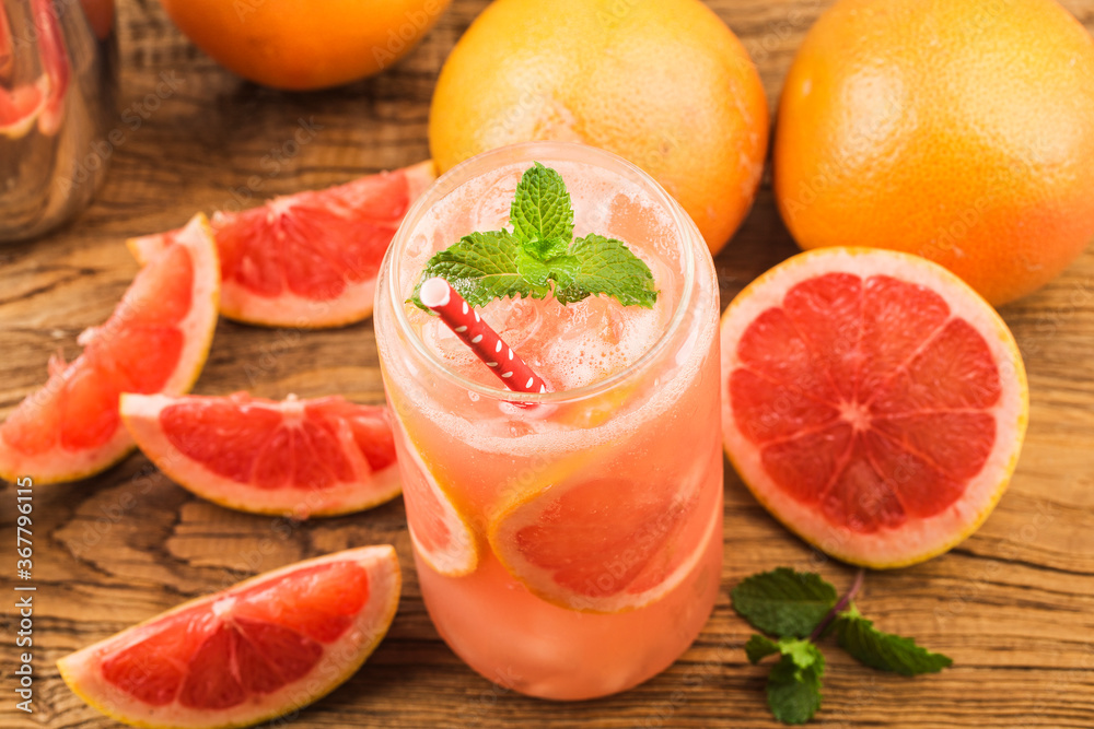 A glass of ripe grapefruit with juice on wooden table close-up