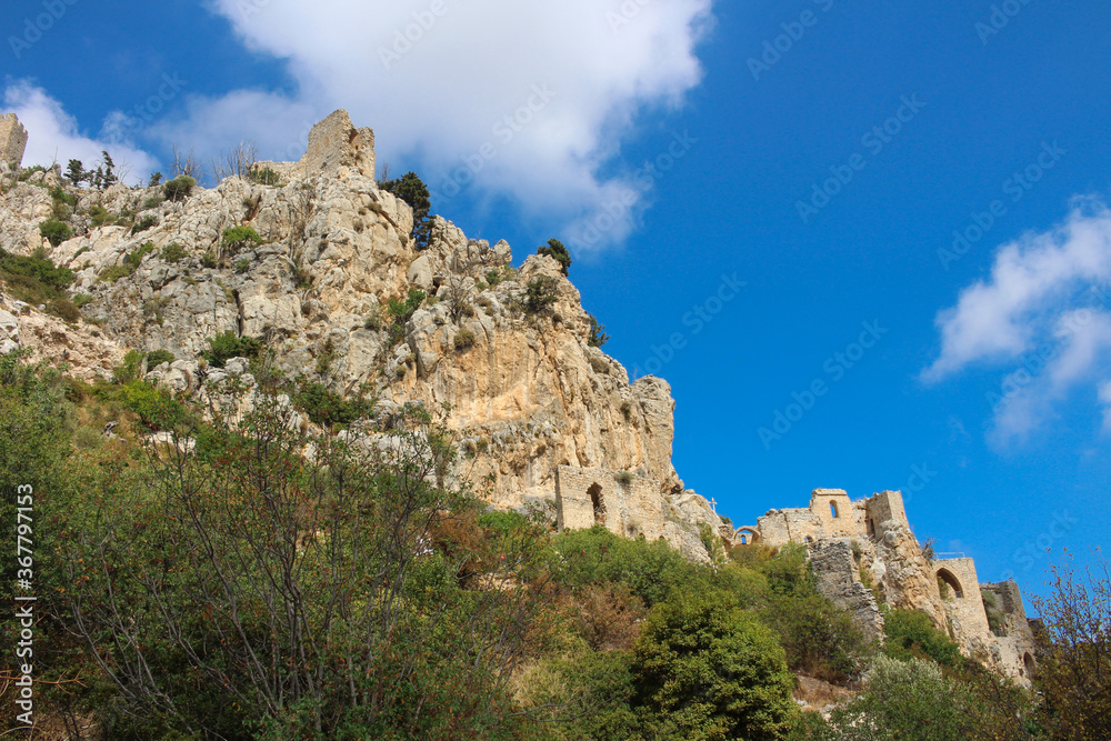 View from below of the stone walls of the castle of Saint Hilarion against a blue sky with clouds. Cyprus.