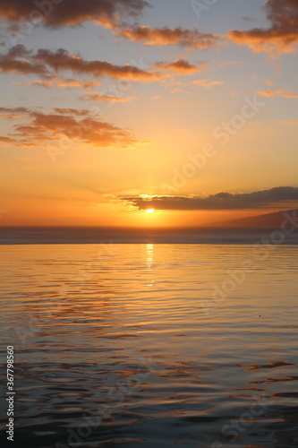 A pool that overlooks the Atlantic ocean, orange sunset, and La Gomera island. © Elena
