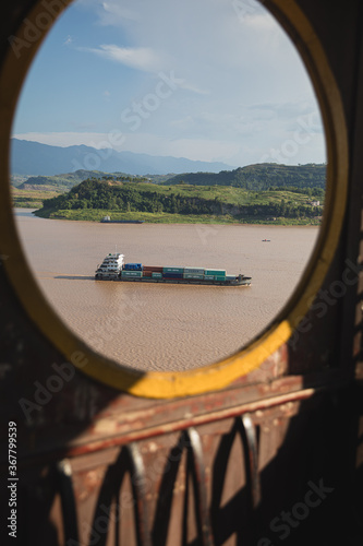 A container ship on the Yangtze river viewed through the window of an ancient temple