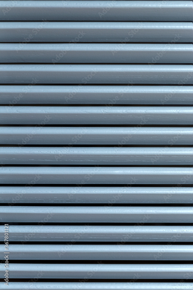 Light through the wooden shutters and blinds. Soft home decor. Retro style. Luxury white indoor plantation shutters, closed shutters Light through the wooden shutters and blinds. Soft home decor. Retro style. Luxury white indoor plantation shutters, closed shutters