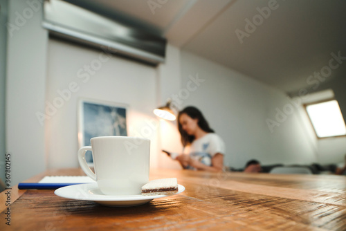 Morning mood. White cup of coffee on a table. Goals and plans on new day. Blurred background of modern apartment.