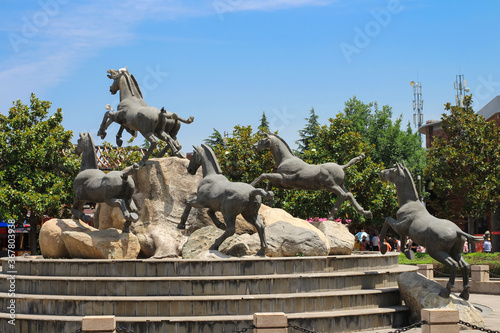 The sculptural composition of the running horses against the blue sky. Xian. China.