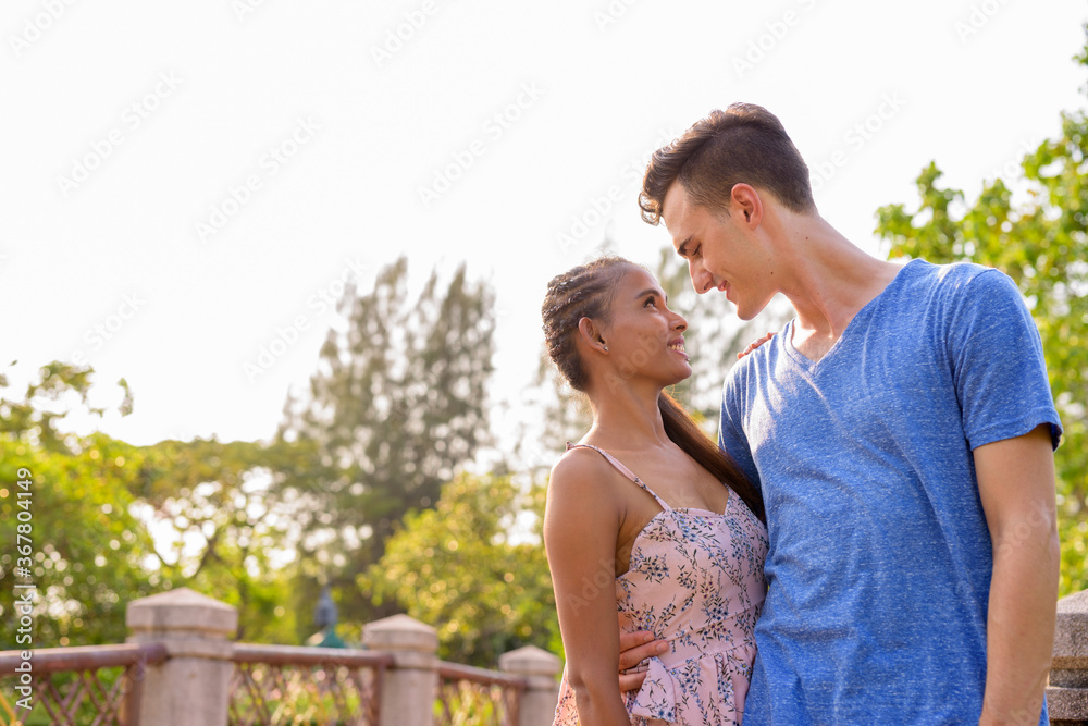 Fototapeta premium Portrait of young multi ethnic couple relaxing together at the park