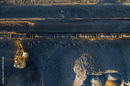 Excavator loads ore into freight cars aerial top view. photo