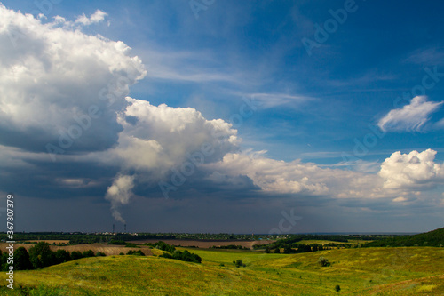 Power plant with a smoking chimney on the background of a summer landscape