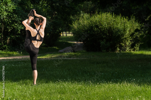 A girl in outdoor sportswear does an exercise for weight loss. Yoga, concept functional training using a rug at sunset