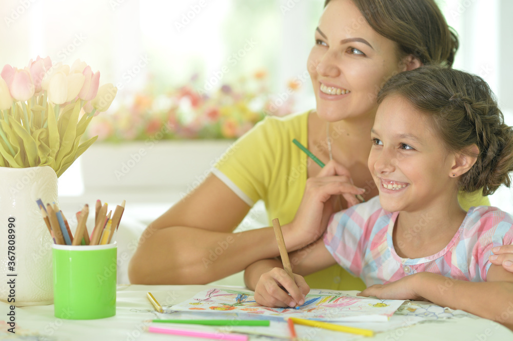 Cute girl with mother drawing at the table at home Cute girl with mother drawing at the table at home