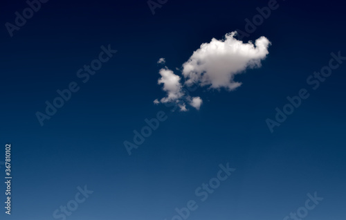 Cumulus clouds look like fluffy  white cotton balls in the sky.  .One small cloud formation in a deep blue sky..........