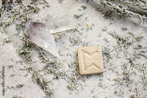 Scandinavian wooden rune PERTHRO on a rough linen cloth with amethyst crystalline, rock crystal and dried wormwood photo