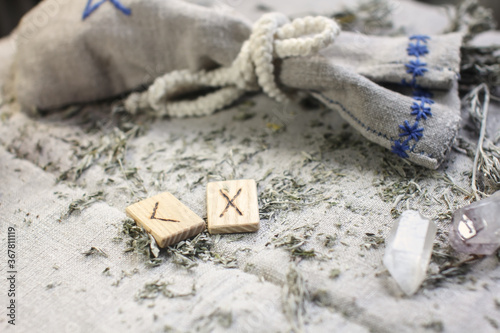 Scandinavian wooden rune Kenaz and Gebo on a rough linen cloth with amethyst crystalline, rock crystal and dried wormwood photo