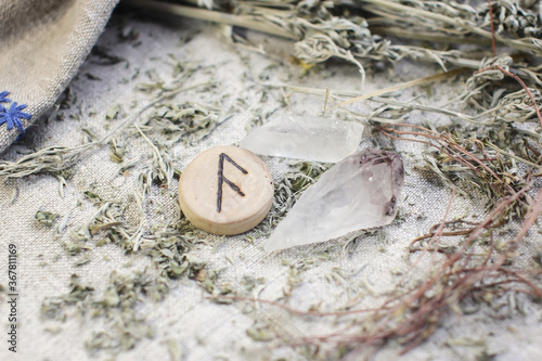 Scandinavian wooden rune Ansuz, As , Oss on a rough linen cloth with amethyst crystalline, rock crystal and dried wormwood photo