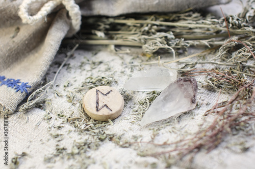 Scandinavian wooden rune PERTHRO on a rough linen cloth with amethyst crystalline, rock crystal and dried wormwood photo