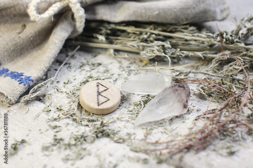 Scandinavian wooden rune Berkana, Beorc,Bjarkan on a rough linen cloth with amethyst crystalline, rock crystal and dried wormwood photo