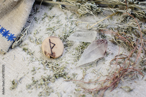 Scandinavian wooden rune Thurisaz, Thurs on a rough linen cloth with amethyst crystalline, rock crystal and dried wormwood photo