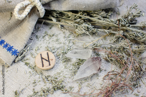 Scandinavian wooden rune Hagalaz, Hagal on a rough linen cloth with amethyst crystalline, rock crystal and dried wormwood