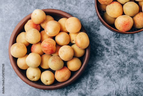 Lots of ripe yellow apricots close up in a crockery on the table