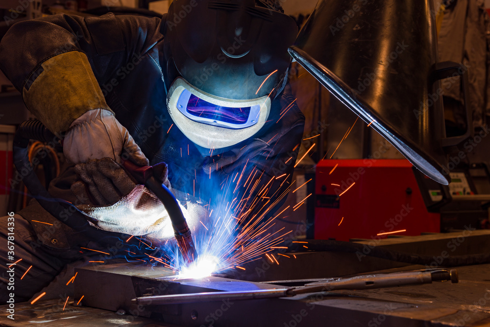 worker with protective mask welding metal and sparks worker with protective mask welding metal and sparks