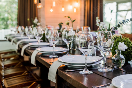 Wedding reception table with Edison bulbs and decor of greenery. Decoe. Wedding table setting