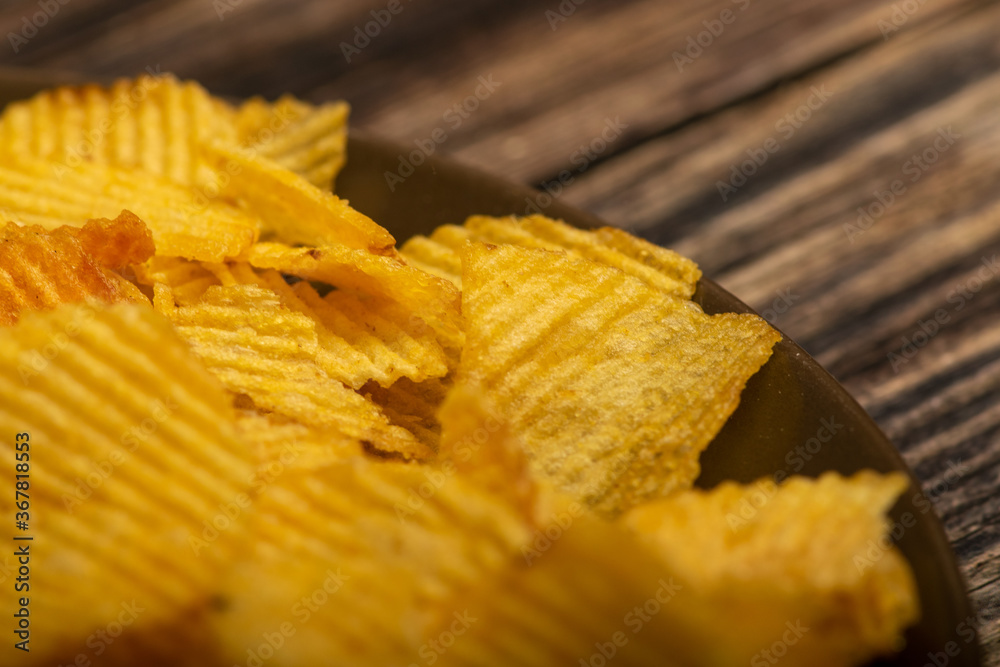 Fluted potato chips on a wooden background. Close up. Fluted potato chips on a wooden background. Close up.