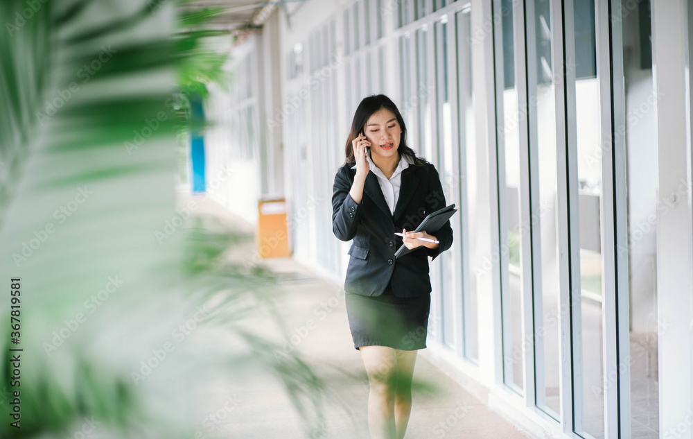 Beautiful asian business woman talking on cellphone while walking outdoor Beautiful asian business woman talking on cellphone while walking outdoor