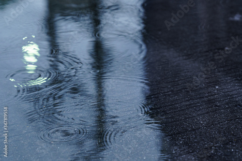 Rain drops rippling in a puddle. the street light refected in the puddle of water