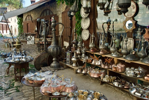 A display of traditional Turkish souvenirs of bronze and copper handcrafted cookware and souvenir hanging from the wall on the pavement waiting for customers. Safranbolu UNESCO Turkey photo