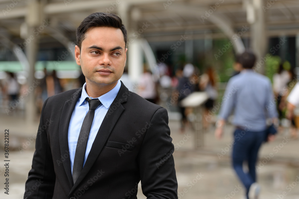Young handsome Indian businessman in the city