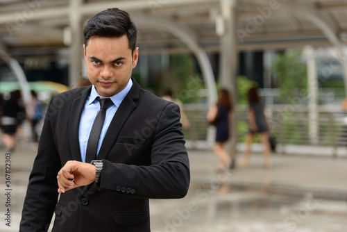 Young handsome Indian businessman in the city