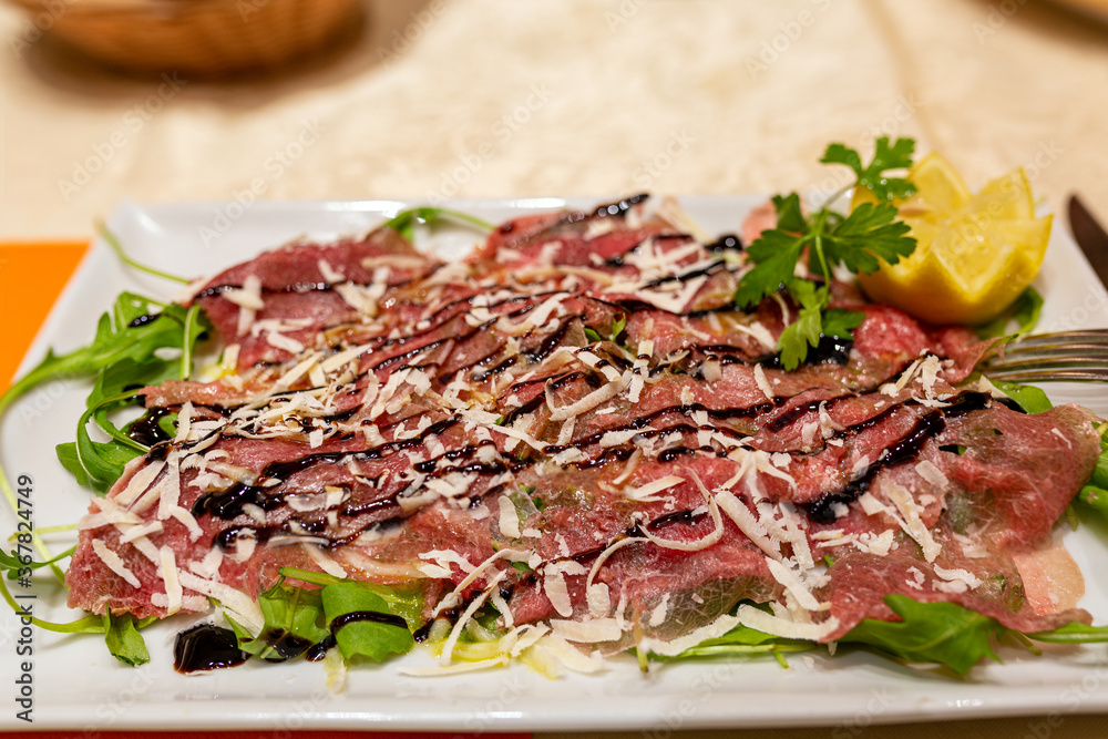 Beef carpaccio. Meat carpaccio with sauce on a white plate.