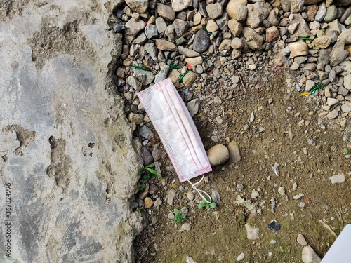 COVID-19 Waste or Litter Concept. Discarded Pink Medical Face Mask Thrown Away After Use on the street footpath.