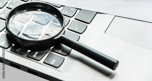 Closeup images of magnifying glass on laptop keyboard, searching, online shopping, and business concept