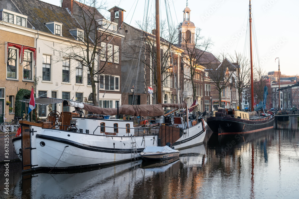 Fototapeta premium Boats moored on canal at Schiedam, Netherlands, with historic houses and reflections