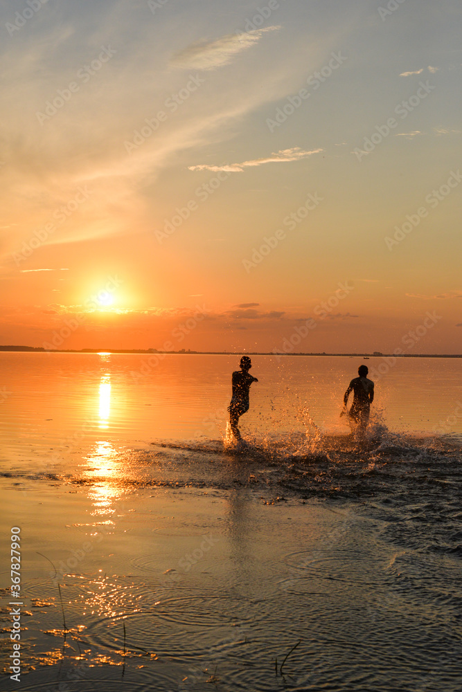 2 young boys running on the lake on sunset time