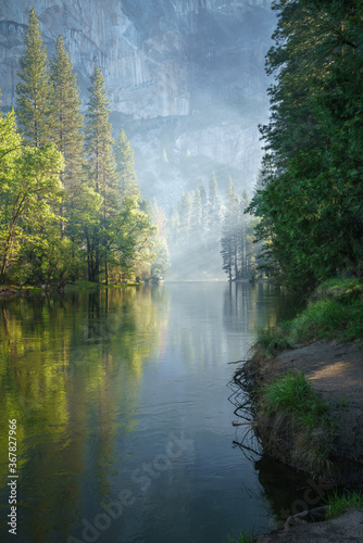 sunbeams on a foggy morning over merced river in yosemite national park