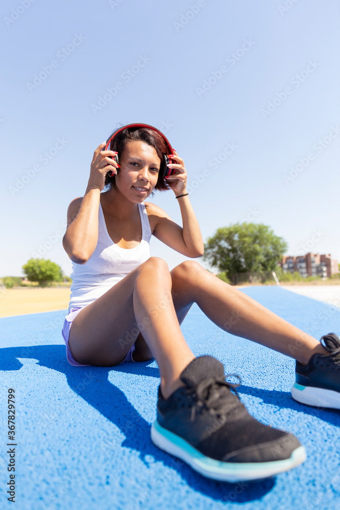 Sporty girl sitting on the floor wearing headphones. Space for text. Lifestyle and sports concept. Sporty girl sitting on the floor wearing headphones. Space for text. Lifestyle and sports concept.