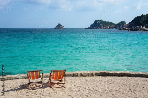 Two bright colored sun loungers against the backdrop of the turquoise sea and rocks. Tailand  Ko-Tao