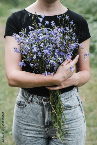 young woman with long hair holds in her hands a bouquet of wildflowers of blue color. rural meadows, farm